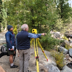 Jerry Davis instructing a student in surveying a creek bed